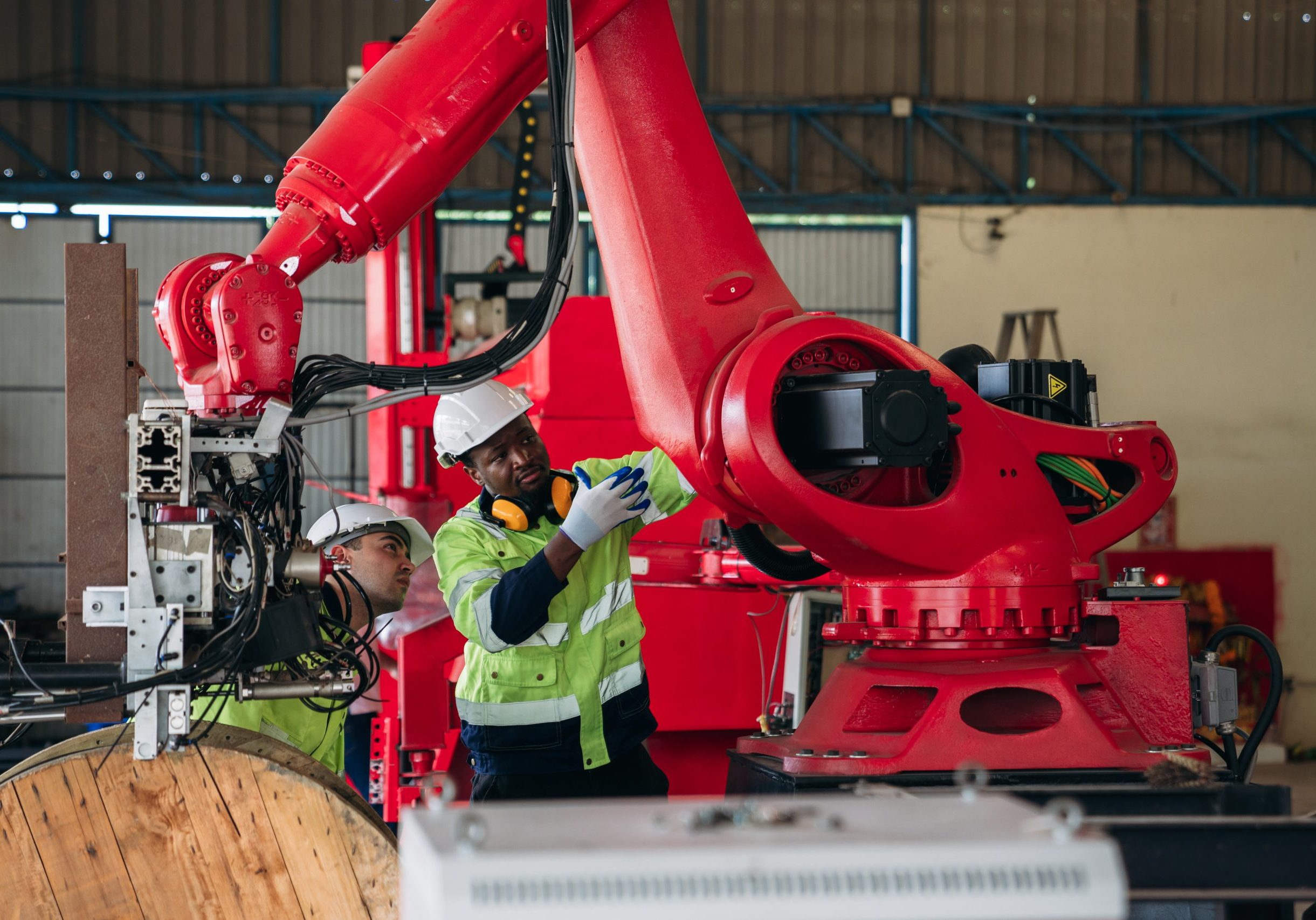 Engineers inspecting and check up machine of the automated arms machine welding robots at factory. Technician controlling the automated arms machine welding robots.